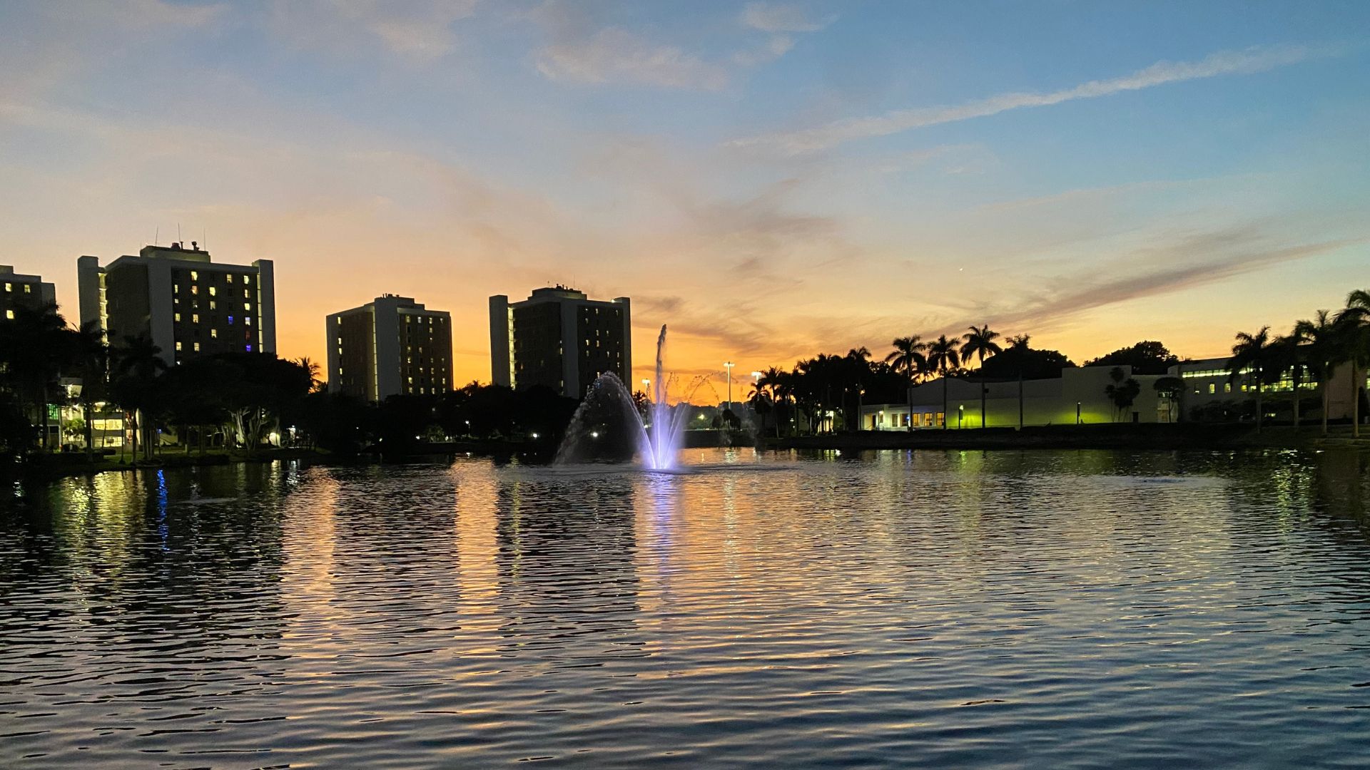 A city in the distance during sunset with a body of water reflecting the sunset